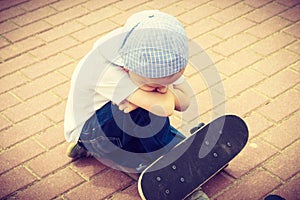 Lonely sad child with skateboard. Loneliness.