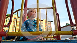 Lonely sad kid in blue clothes on the playground