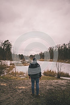 Lonely sad man, standing with his back and looking at frozen lake inforest. Depression, bad mood and suicidal thoughts. I need
