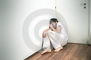 Lonely sad man suffers from depression and crying on floor