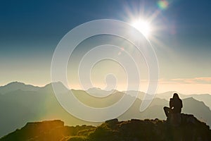 Lonely sad person sits on summit of mountain photo