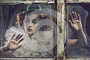 A lonely sad pierrot woman behind the glass photo