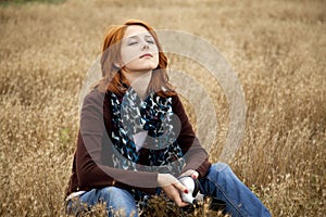Lonely sad red-haired girl at field