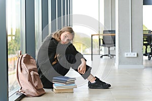 Lonely sad schoolgirl while all her classmates ignored her. Social exclusion problem. Bullying at school concept.