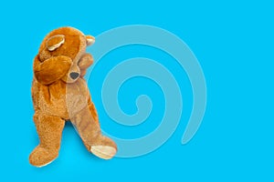 Lonely sad teddy bear on blue background