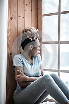 Lonely sad woman looking out window on windowsill