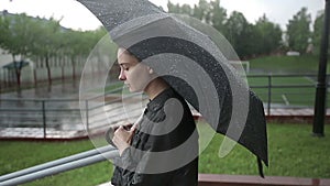 Lonely sad woman walks down the street in heavy rain. Slow motion