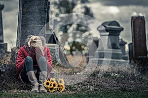 Lonely Sad Young Woman in Mourning in front of a Gravestone