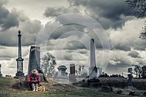 Lonely Sad Young Woman in Mourning in front of a Gravestone