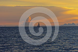 Lonely sailboat in the sea with orange sky