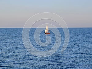 Lonely sailboat in the sea under blue sky