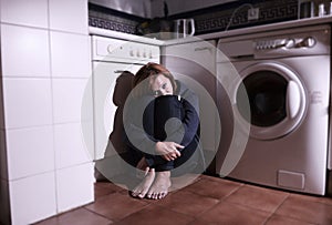 Lonely scared and sick woman sitting on kitchen floor in stress depression and sadness