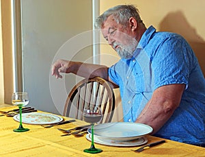 Lonely senior man at the dinner table. Bereavement.