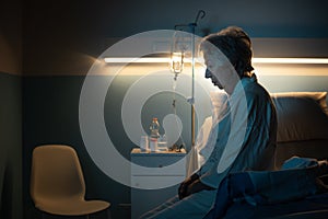 Lonely senior patient sitting on the hospital bed at night