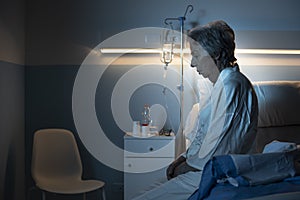 Lonely senior patient sitting on the hospital bed at night