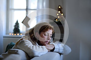 Lonely senior woman sitting and sleeping on sofa indoors at Christmas, solitude concept.