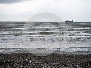 lonely ship in the middle of a rough sea. Barge in the distance. Big waves on the sea. After the storm. Bad weather. Ship on the