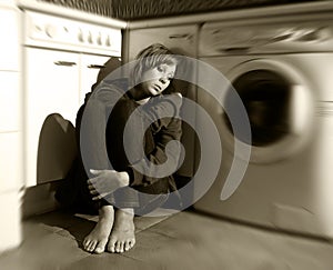 Lonely and sick woman sitting on kitchen floor in stress depression and sadness