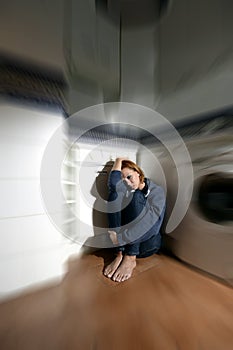 Lonely and sick woman sitting on kitchen floor in stress depression and sadness