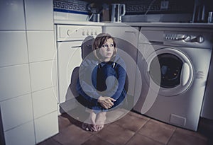 Lonely and sick woman sitting on kitchen floor in stress depression and sadness