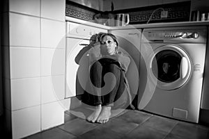 Lonely and sick woman sitting on kitchen floor in stress depression and sadness