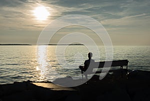 Lonely Single Boy sitting on Bench at Coast