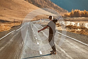 Lonely skateboarder on longboard at mountain road
