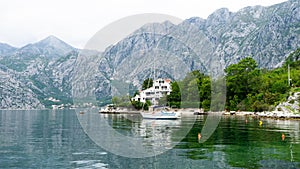 Lonely small boat in a fisherman village in the bay of Kotor. Lake surrounded by grey big mountains and green brushes. Landscape