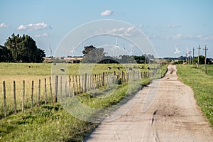 lonely straight road through the countryside, and wind power mills farm on the horizon photo