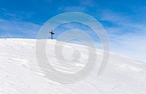 Lonely Summit Cross on windswept snow mountain with blue Sky. Rangiswanger Horn, Alps, Allgau, Bavaria, Germany.