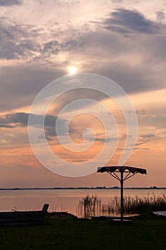 Lonely sunshade with sunset over the lake background