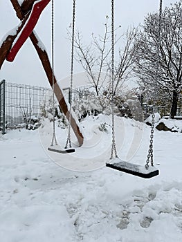 Lonely swings at empty children's playground covered with snow. Winter solitude. Prague.