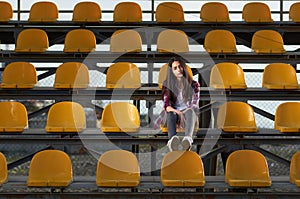 Lonely teen girl sitting on tribunes,