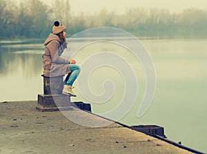 Lonely teenage girl sitting on the dock