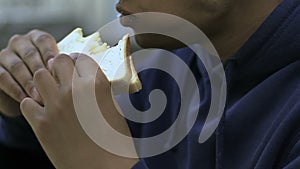 Lonely teenager eating sandwich in school canteen, outsider, racial problem