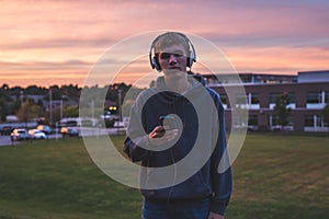 Lonely teenager listening to music at sunset.