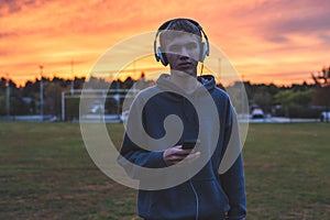 Lonely teenager listening to music at sunset.