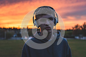 Lonely teenager listening to music at sunset.