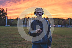 Lonely teenager listening to music at sunset.