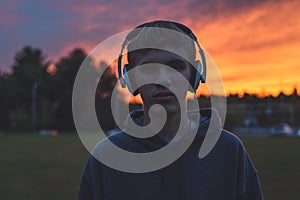 Lonely teenager listening to music at sunset.