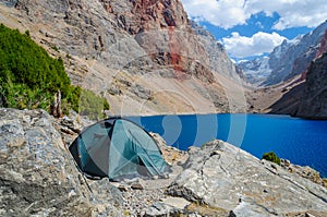 Lonely tent stands on the shore of a beautiful mountain lake