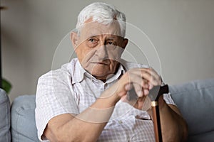 Lonely tired depressed senior old man sitting on sofa home