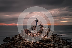 Lonely traveler on the top of the Giant`s Causeway at sunset, Northern Ireland