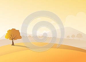 Lonely tree on a hill with mountains background in sunset view.Beauty autumn field and a tree scenery.