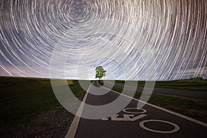 Lonely tree under the beautiful star trails in the starry night.
