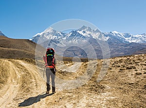 Lonely trekker on a crossroad of two roads towards mountains.