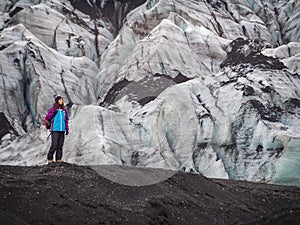 Lonely turist girl near a glacier on black vulcano sand