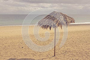 Lonely umbrella on the beach. Vintage parasol, retro photo.