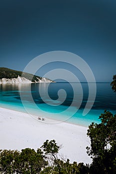 Lonely unrecognizable tourist couple under sun umbrella chill relax on beautiful idyllic pebble beach with crystal clear