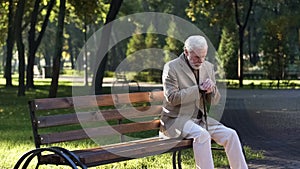 Lonely upset old man sitting alone in park and thinking about life, pensioner